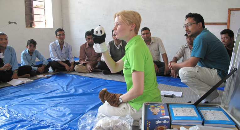 Medlem i beredskapsgruppen, specialläraren Johanna Kurki visar nepalesiska lärare hur man med hjälp av handdockor kan hjälpa barn att berätta om sina känslor och erfarenheter. Bild: Tuomas Väisänen.