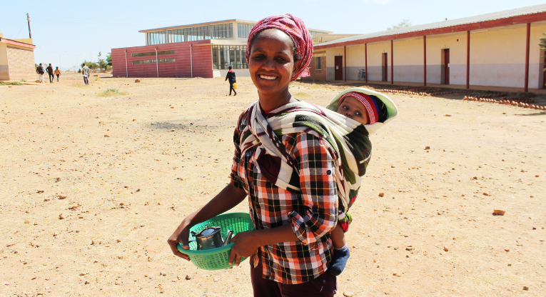 Miliete Tsefa, who works at one of the teacher training institutions in Eritrea, College of Education in Mai Nefhi, is standing with her child in front of a recently built campus library. Photo: Laura Vanhanen.