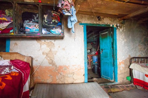 Part of the a cracked wall of Muktan’s family’s old house serves as a wall in their hut. The hut is home to six people.