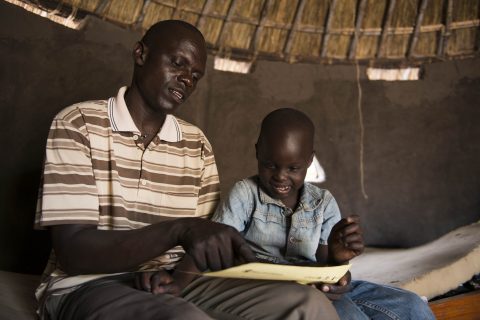 Thesame and his father John inside their tuku at a refugee settelemnt in Adjumani.