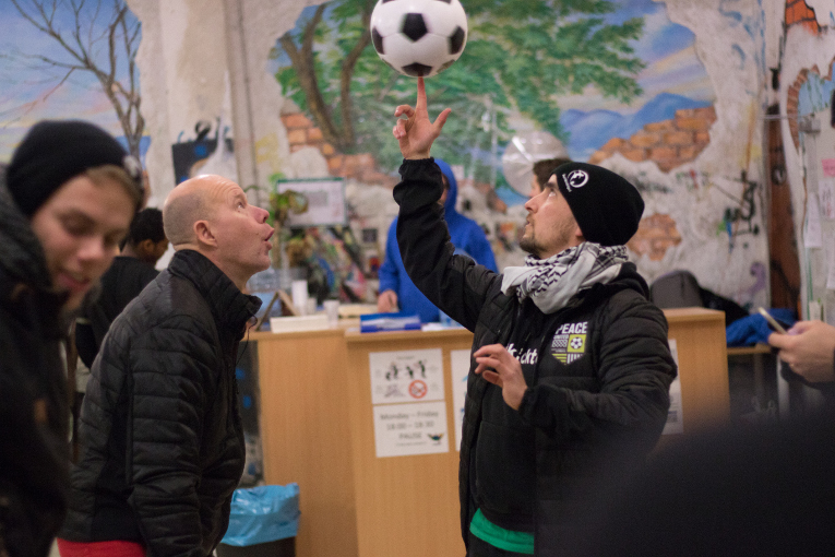 Jan Saddei koordinoi pakolaisten jalkapalloharjoituksia Münchenissä Buntkicktgut-järjestössä. Kaj Kunnas ihailee Janin pallotekniikkaa Peace United -turnauksen yhteydessä.
