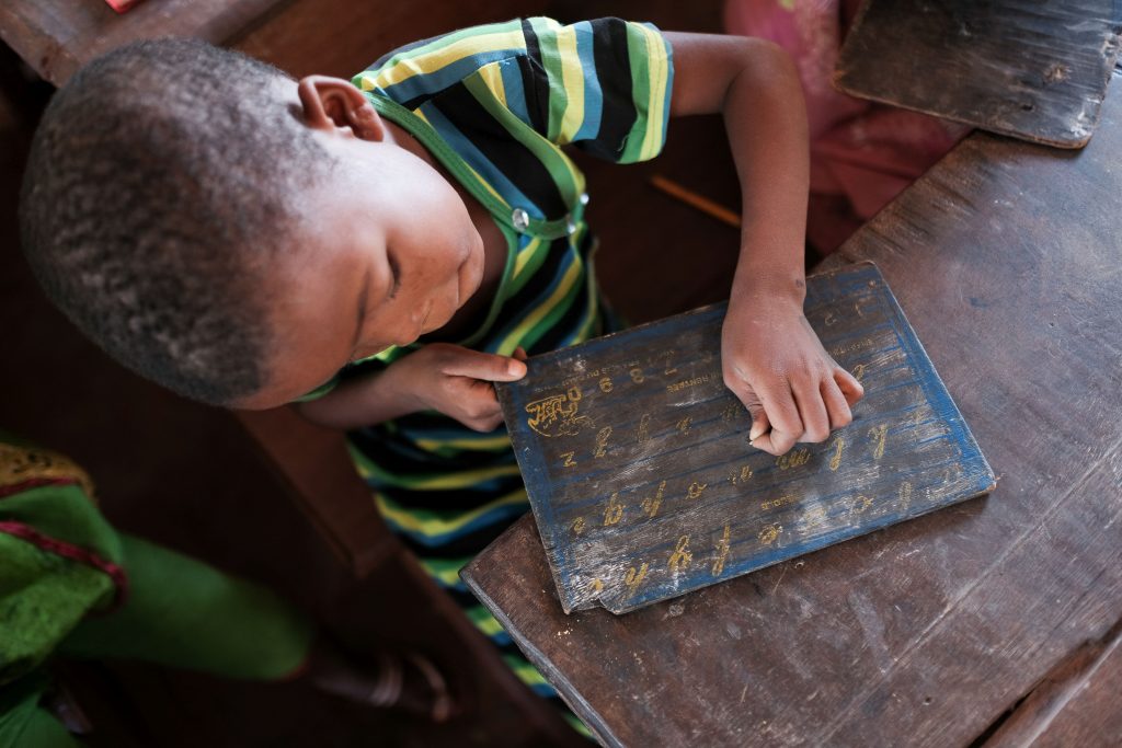 Keskiafrikkalainen koululainen harjoittelee kirjaimia.