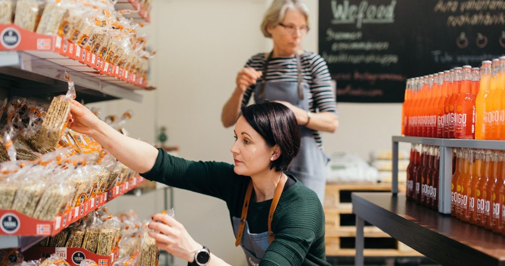 Kaksi työntekijää hyllyttää WeFood-kaupassa.