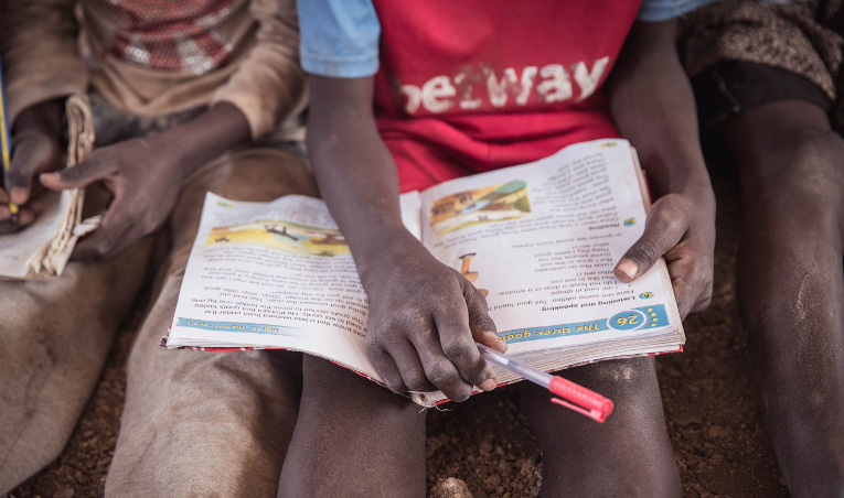 A kenyan student with a book on his lap.