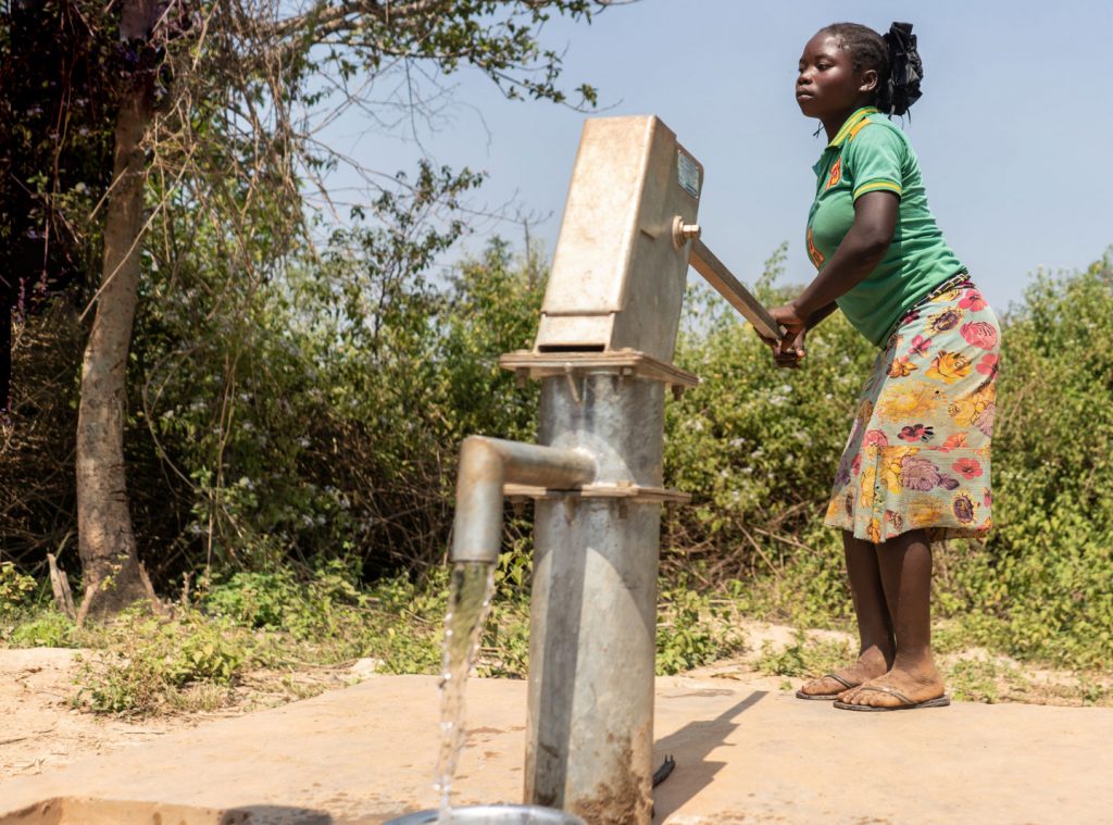 Nainen pumppaa vettä kaivosta aurinkoisena päivänä