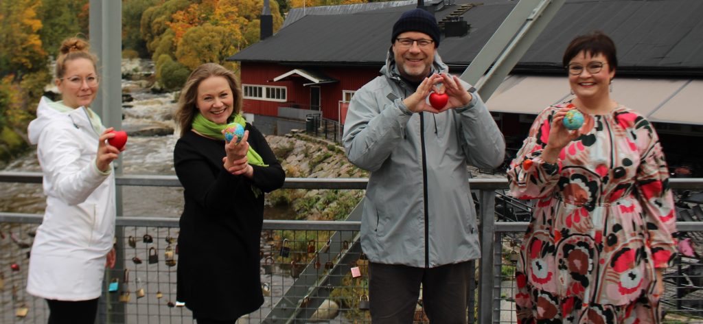 Neljä ihmistä seisoo sillala ja katsoo kameraan.