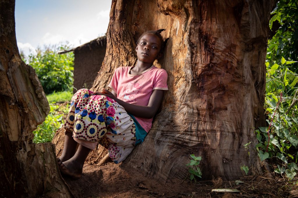 Nuori tyttö istuu ison puun juurella