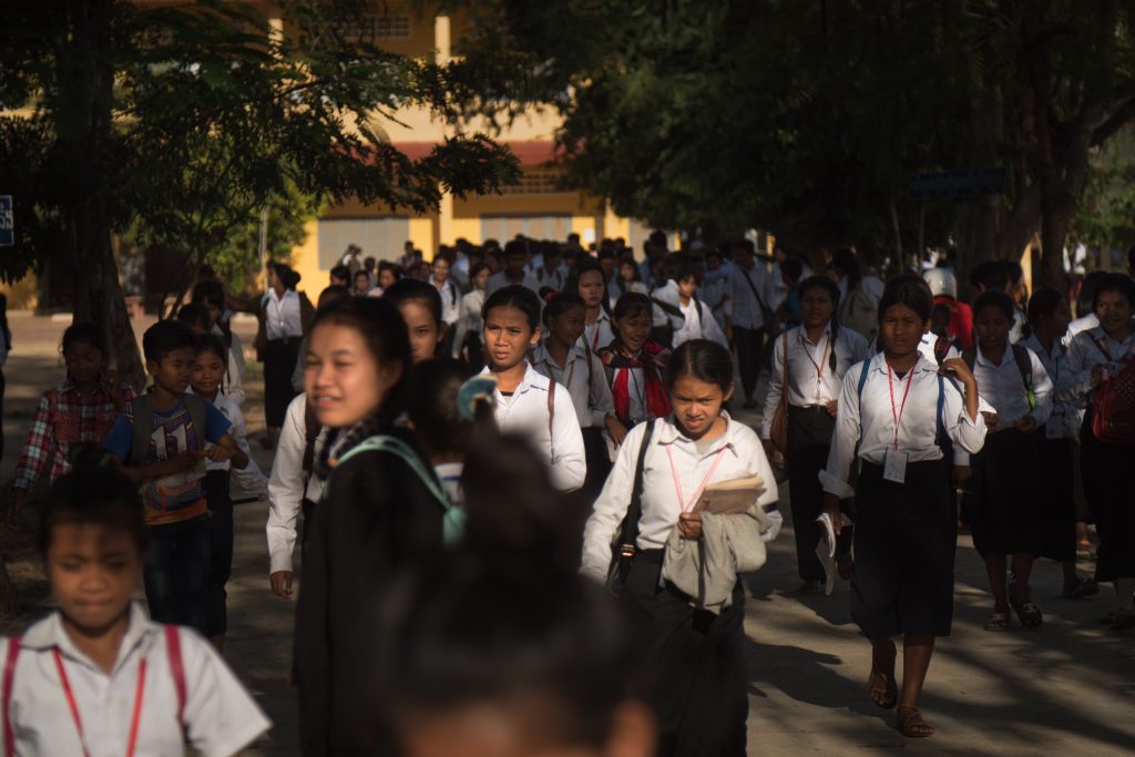 A large group of people walking in school uniforms outdoors.