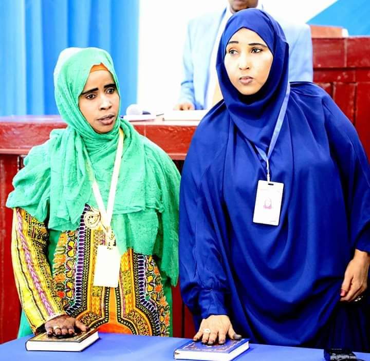 Two women holding their hands on a book on the table.