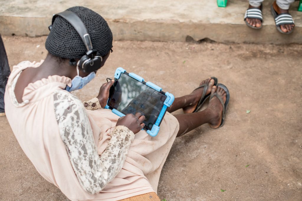 A girl sits on the ground studying with a tablet.