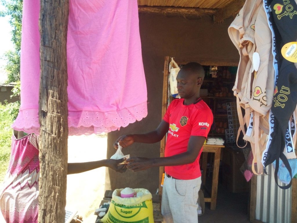 Alex Lojuan attending to a customer at his Retail shop located in Odraji Village, Zone 1 – Palorinya settlement