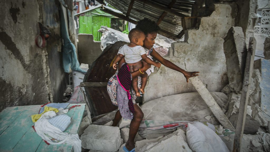 Nainen kantaa lastaan Haitin maanjäristyksessä tuhoutuneessa kodissaan.