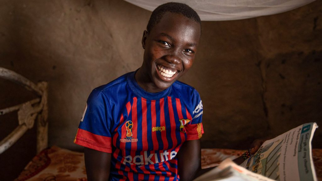 Tyttö hymyilee kameralle kotonaan Etelä-Sudanissa.