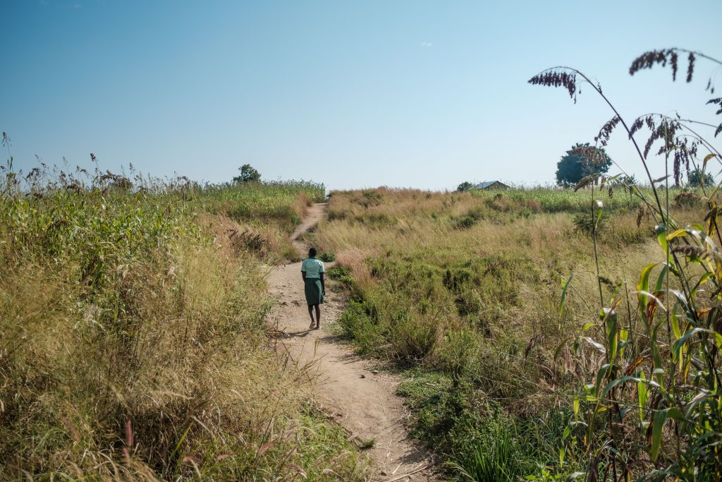 A girl walking though grass fields