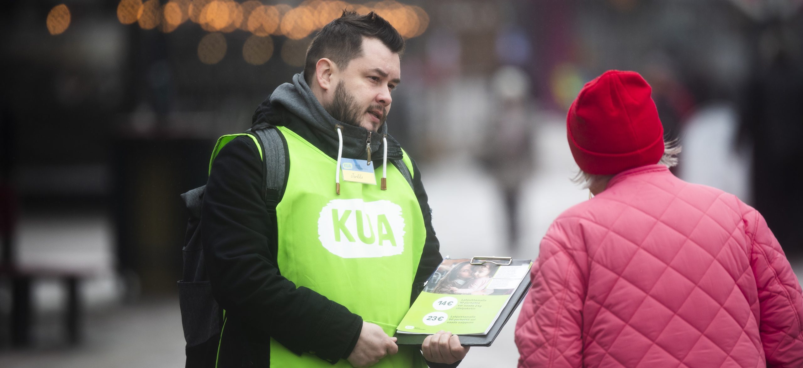 Feissari keskustelee kadulla ohikulkijan kanssa. 