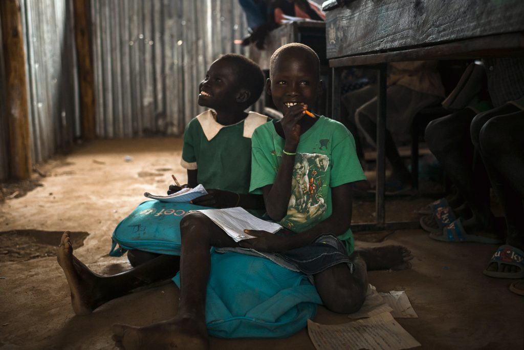 Two Kenyan children sit on the floor of a classroom