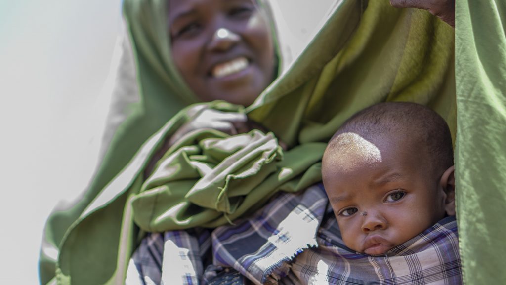 Lapsi katsoo äitinsä sylistä Somaliassa. Lapsen ympärillä on äidin vaatetta.