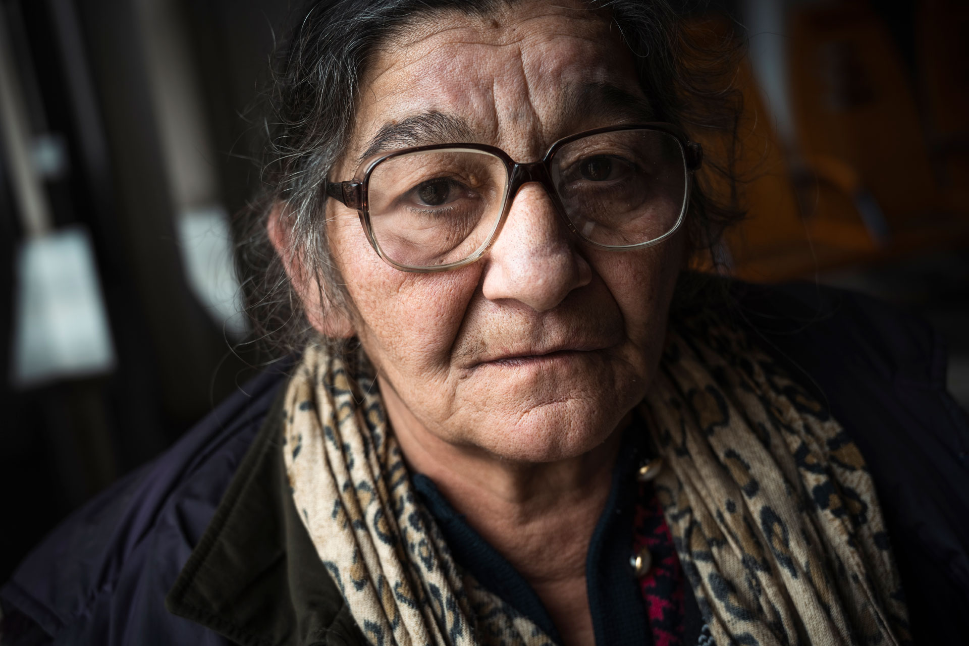 An older woman in glasses looks at the camera