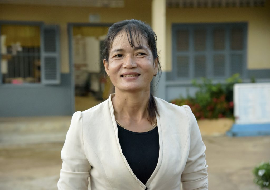 A woman stands in front of the school.