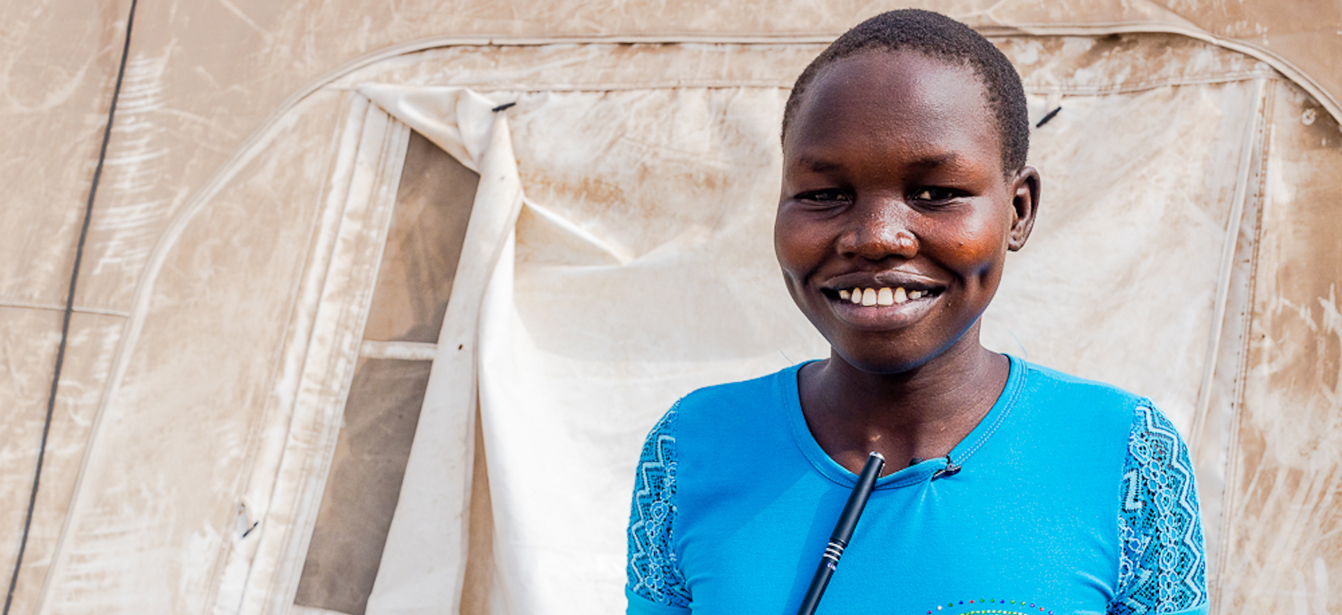 A schoolgirl stands in front of a temporary classroom