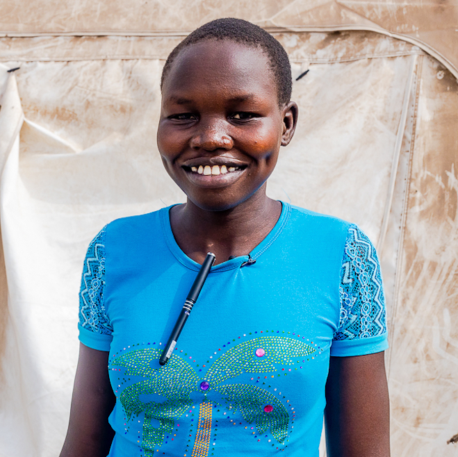 A schoolgirl stands in front of a temporary classroom