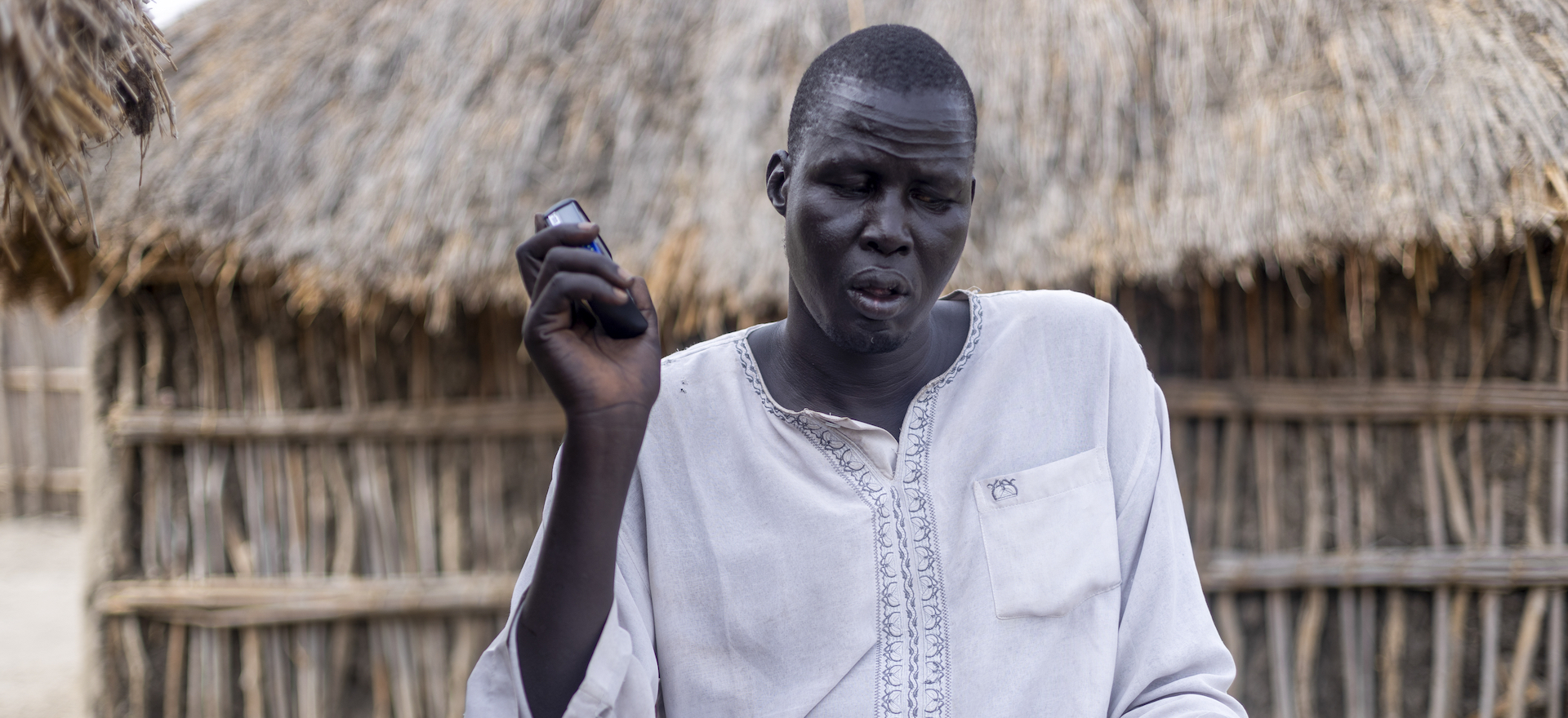 A man sits listening closely to a hand held recorder