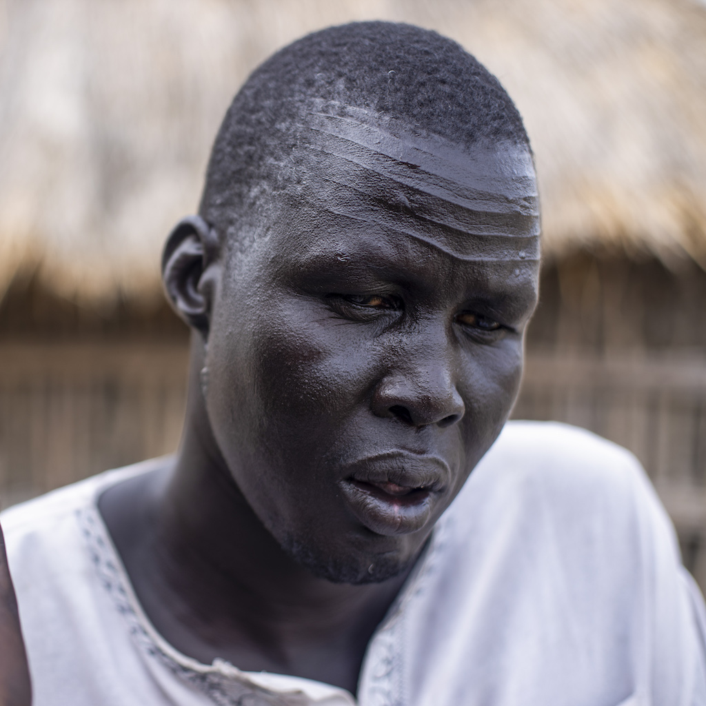 A man sits listening closely to a hand held recorder