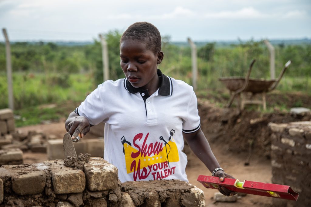 A woman laying bricks in Uganda.