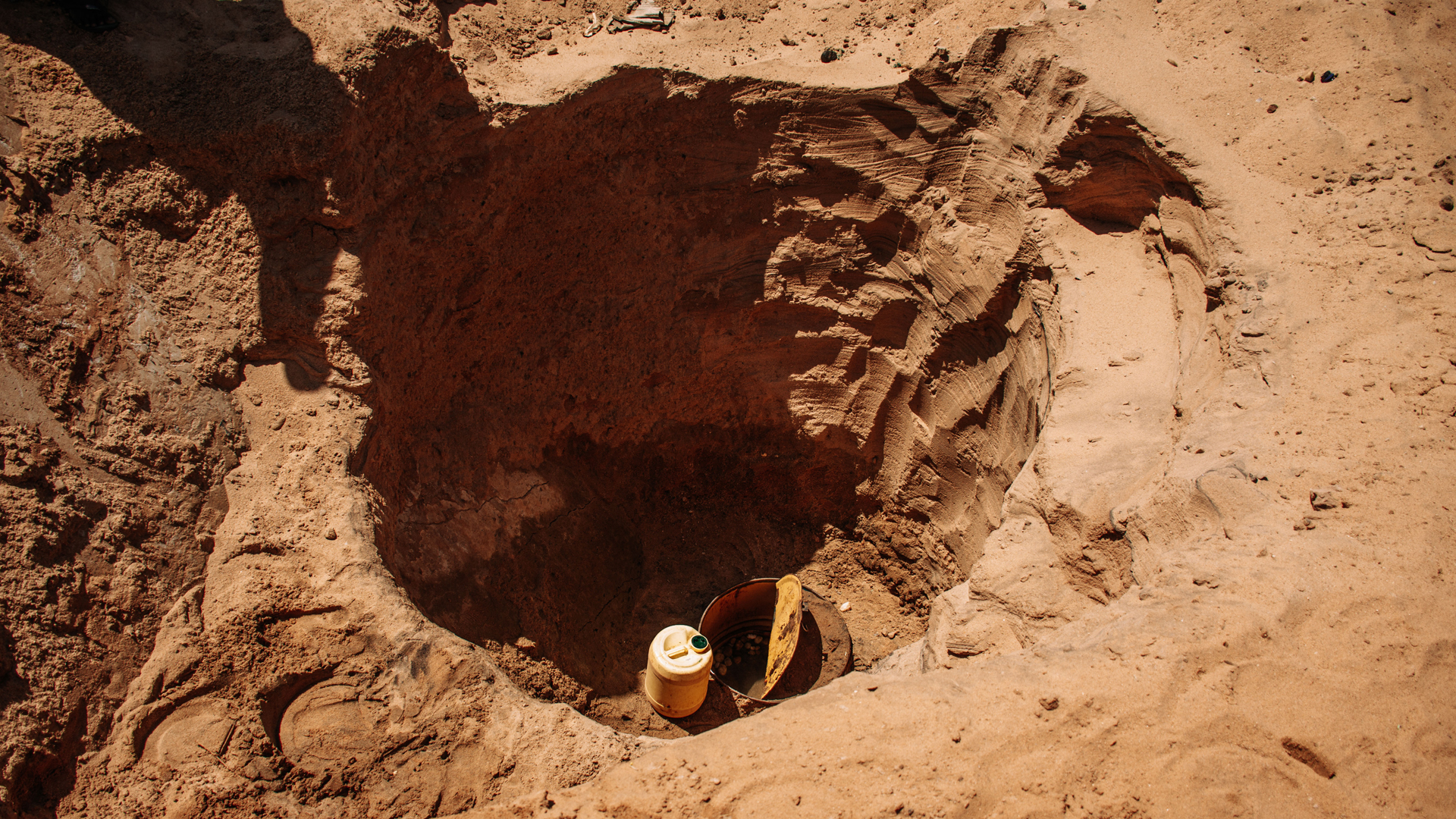 Ylhäältä otettu kuva kuivuneesta kaivosta Keniassa. Kaivon pohjalla on astia.