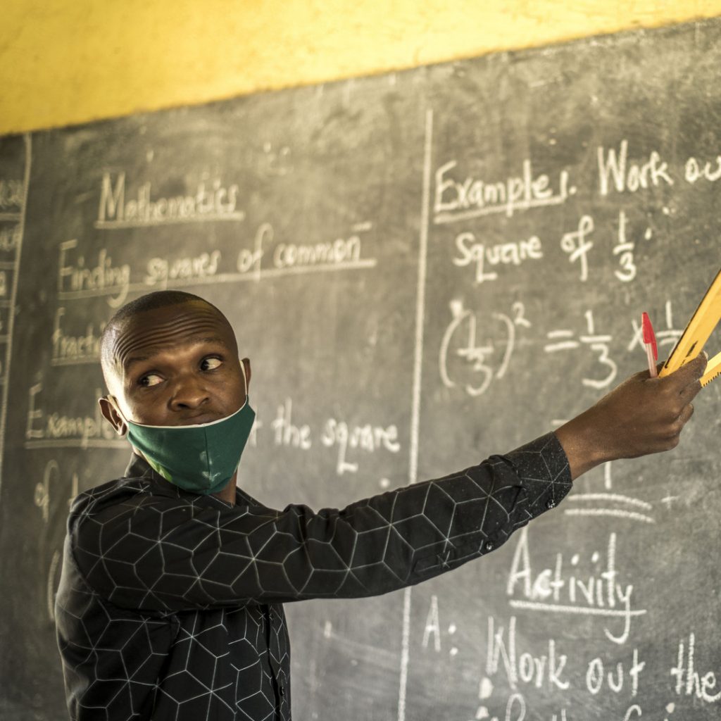 Opettaja osoittaa liitutaululle Ugandassa. Kuva: Hugh Rutherford