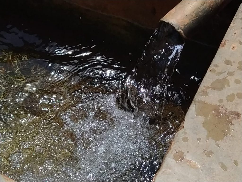 Close up shot of water pouring out of a pipe in a borehole