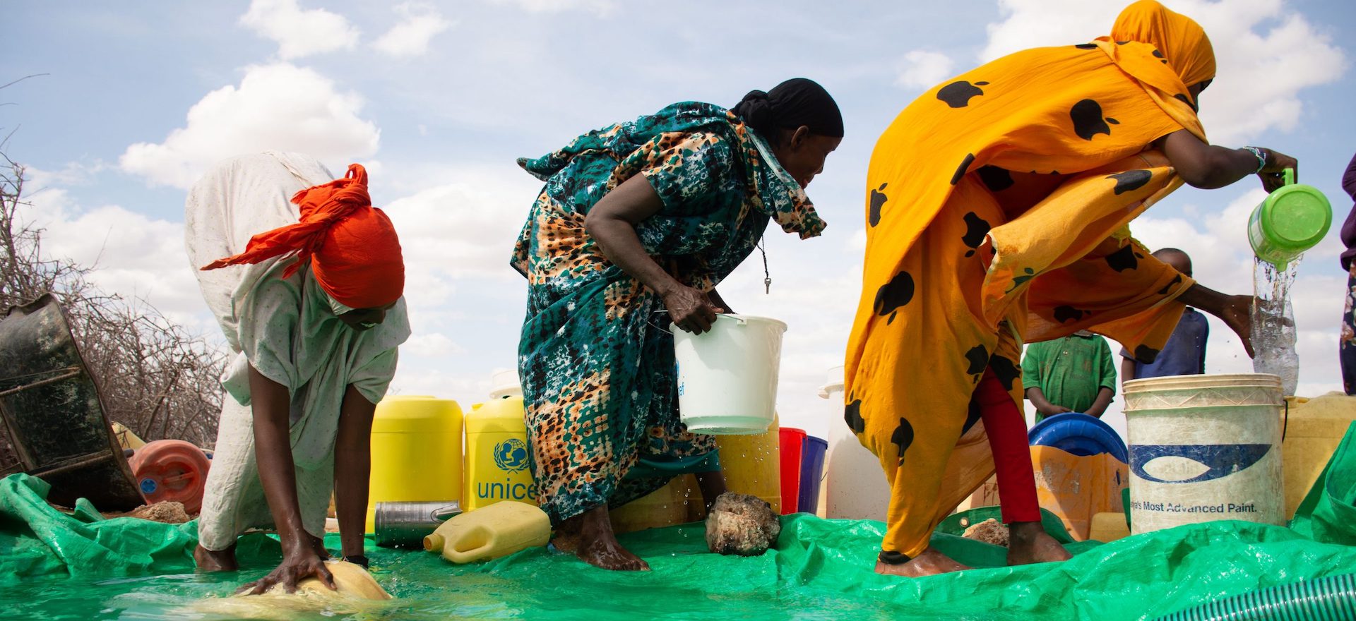 Women fetching water from a makeshift shallow well.
