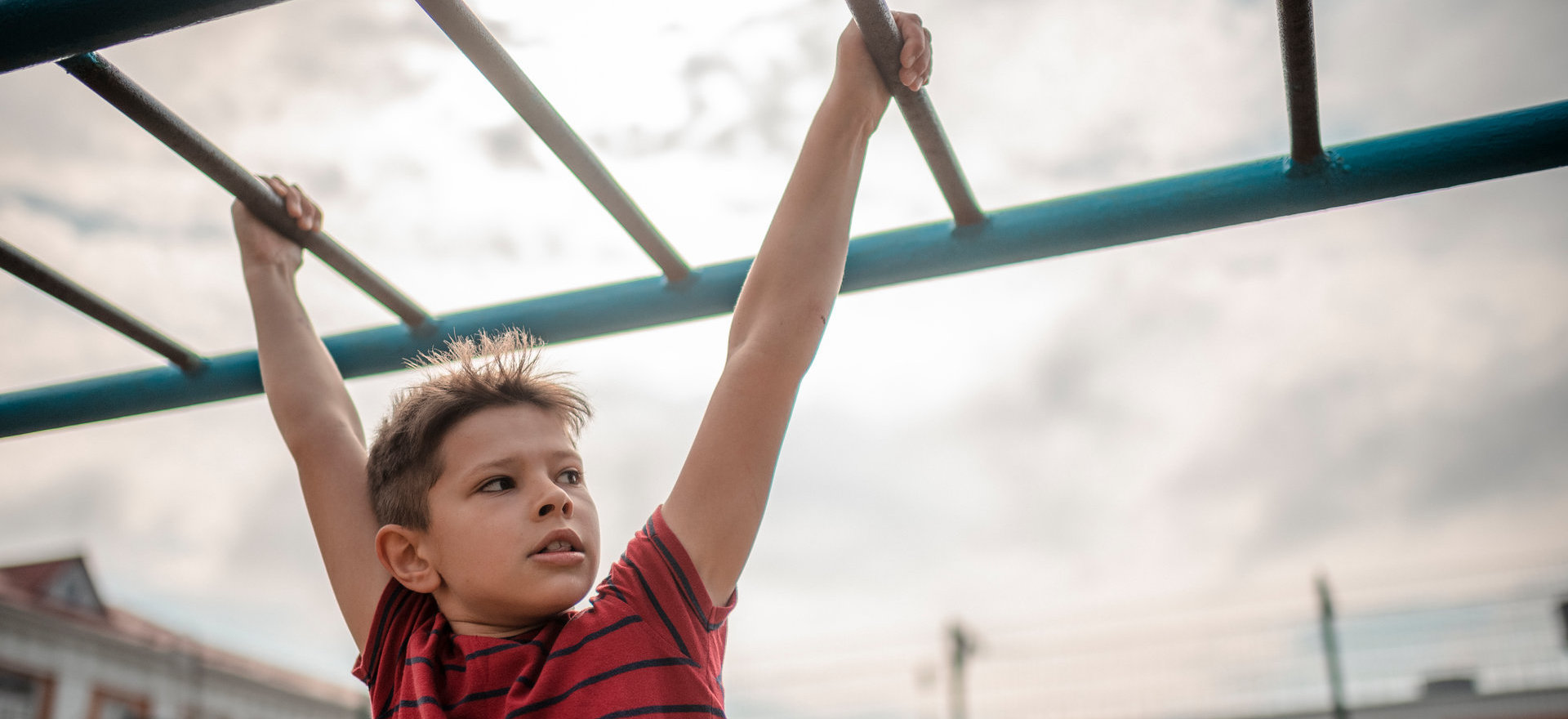 A boy swings from monkey bars in a playground