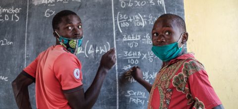 Two boys draw on a blackboard in Uganda.