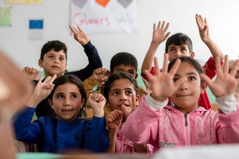 Luokkahuoneessa istuvat lapset viittaavat Syyriassa.
