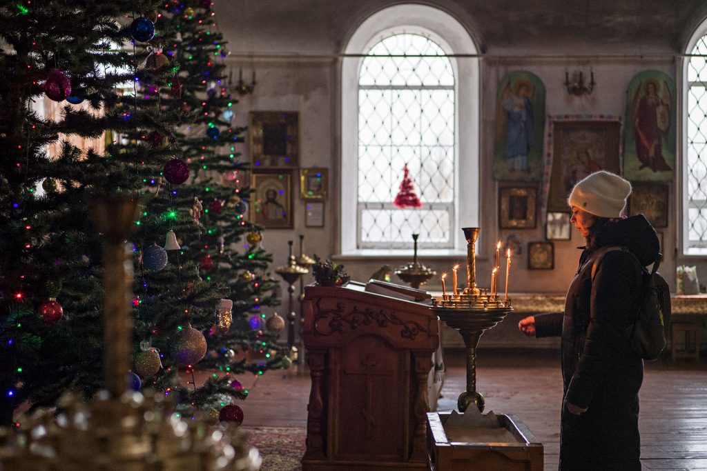 Tyttö seisoo jouluksi koristellussa kirkossa Ukrainassa. 