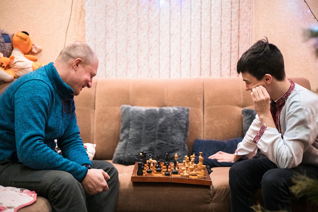 Mies ja poika istuvat sohvalla pelaamassa shakkia Ukrainassa. 