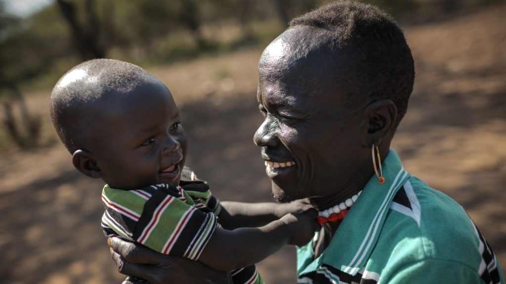 Vauva hymyilee miehen sylissä Keniassa.