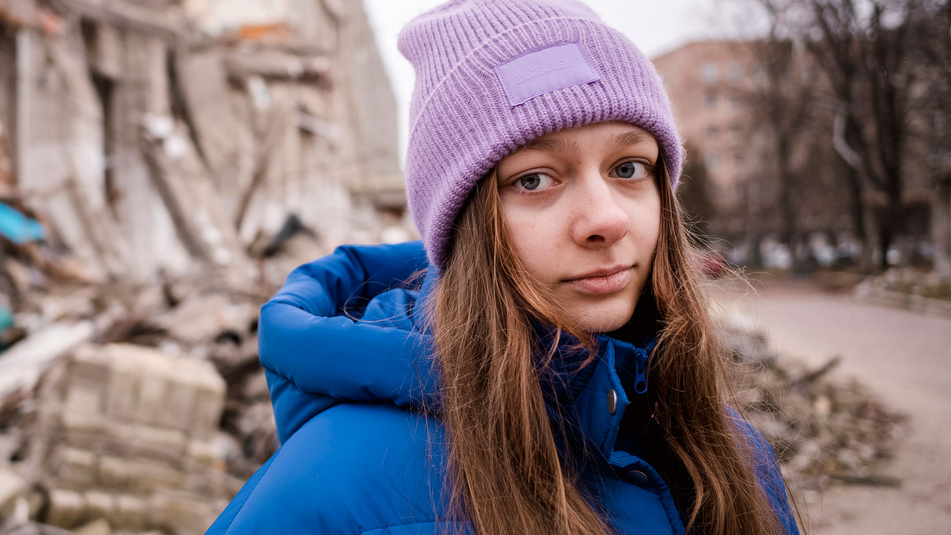 Kateryna Tkachenko, 9th grader at Lyceum Number 25 in Zhytomyr, Ukraine looks at the camera standing in front of the destroyed school.