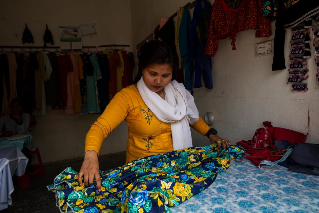 A woman inspects a piece of clothing on a table.