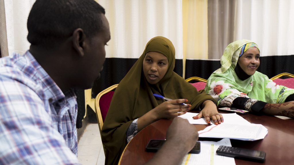 A woman in a meeting speaks to a man sitting next to her