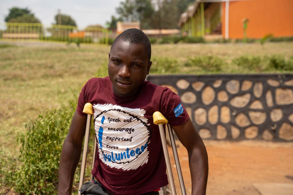 A picture of a Ugandan youth with crutches on the school yard