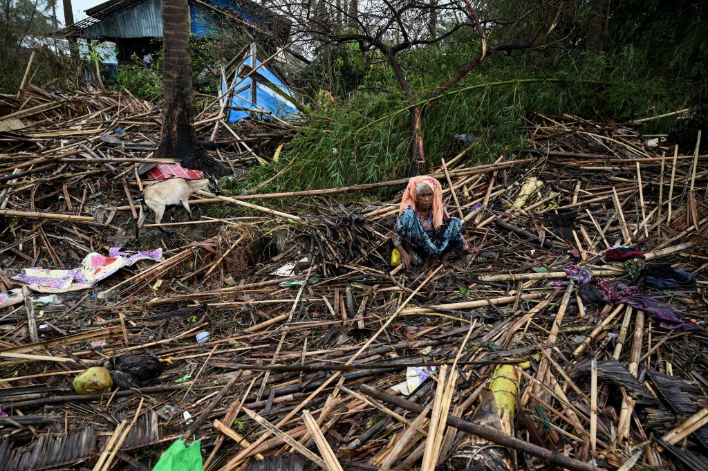 An old woman sits in the ruins of her house