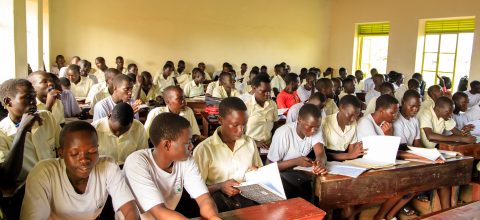 A classroom full of adolescent students sitting at desks, reading and studying.