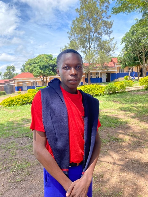 A young man stands outside in front of a school building