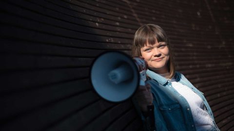 Nainen istuu pimeässä huoneessa.