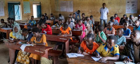 Elever sitter och skriver vid sina skrivbord i en grundskola i flyktingbosättningen Rwamwanja, Uganda.