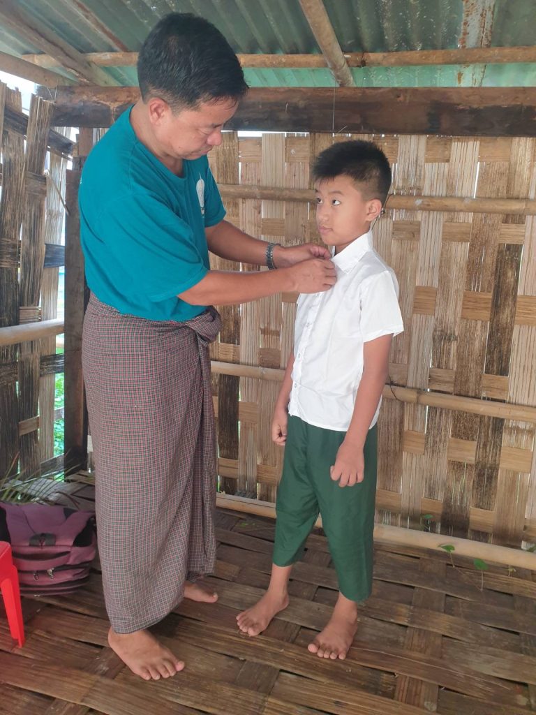 A father helps his son button up his shirt