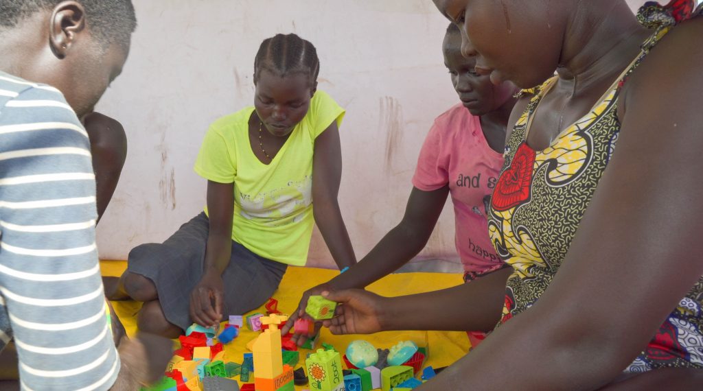 A number of girls sit around DUPLO bricks playing together