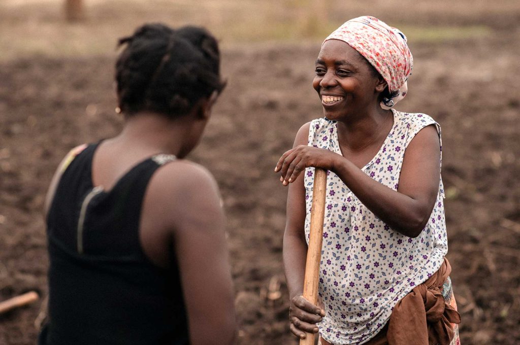 Två kvinnor pratar på en åker i Uganda.